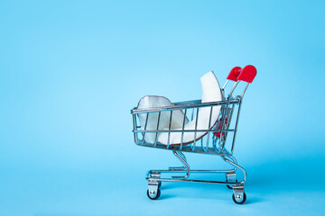 Creative concept of coconut slices in a miniature shopping cart against a bright blue background, symbolising fresh grocery shopping and tropical vibes.