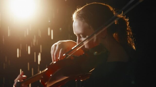 Lonely woman with violin in rain in night, express emotions by classical music, silhouette of pretty talented lady with viola and bow in darkness, fascinating slow motion shot with female musician