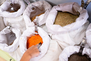 Customer picking red lentils from bulk bins at zero waste shop