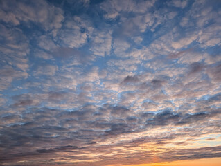 Beautiful sky with fluffy clouds at sunset or sunrise, ideal natural background or texture for your design projects.