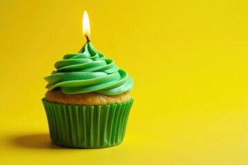 Green-frosted cupcake, lit candle, yellow background, sweet, cake, confectionery