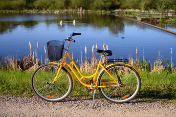Fototapeta premium Beautiful yellow bicycle near a pond or a lake. Spring or summer nature Sweden 