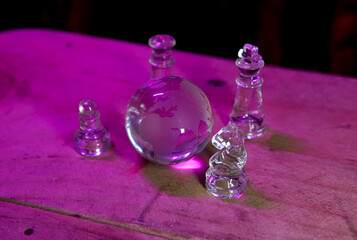 Glass chess pieces, board, and globe for global business