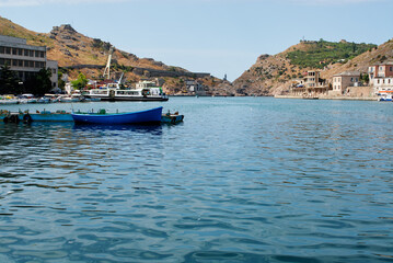 Fototapeta premium Serene Coastal Village with Blue Boat in Picturesque Harbor Setting..