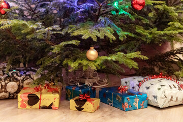
The bottom of a Christmas tree with presents wrapped in colorful paper and decorated with bows,...