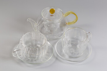 Empty glass teapot and different double-walled cups on saucers