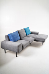 Modern Gray Sofa with Blue Accent Cushions Against White Background..