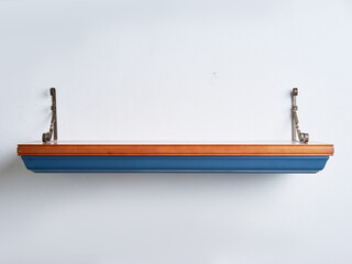 Elegant Wooden Shelf With Ornate Metal Brackets Against White Wall