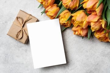 Obraz premium Blank greeting card mockup with tulips flowers bouquet and gift box, white card mock up with copy space
