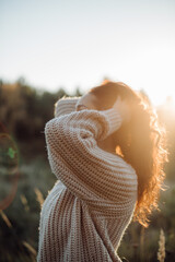 Woman holding hair enjoying golden hour sunlight in nature