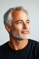 Obraz premium A joyful man with a trendy and modern hairstyle. Pure white solid background. Elegant men's ivy league haircut - midlife white man with grey hair. Visual idea layout of style for aging men.