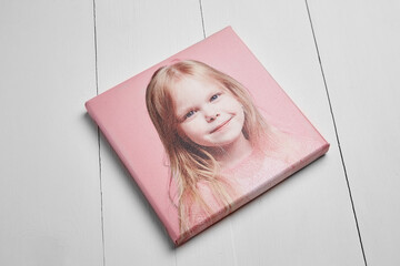 A high-quality stretched canvas print featuring a portrait of a smiling young girl with blonde...