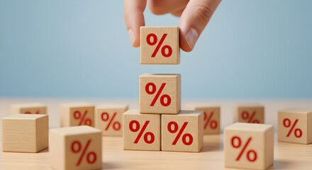 Hand Placing Percentage Blocks on Wood Surface against Light Blue Background
