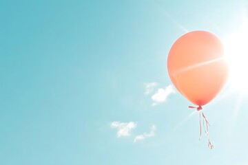 Fototapeta premium Orange balloon floats in a vibrant blue sky, sunlight shining behind it. A few small, fluffy white clouds are visible near the balloon. The scene is bright, airy, and evokes a feeling of joy and