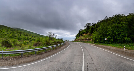 Road Trip the Hill to the Sea. Empty long mountain road to the horizon on a sunny summer day with...