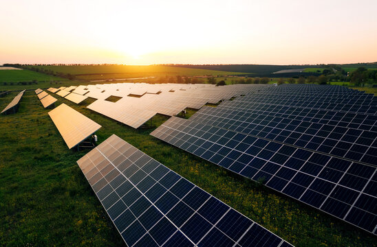 Aerial view of a solar farm generating solar energy.Solar panels park generating green energy electric at sunset.Green energy reduce carbon emissions and makes earth cleaner and more ecological.	
