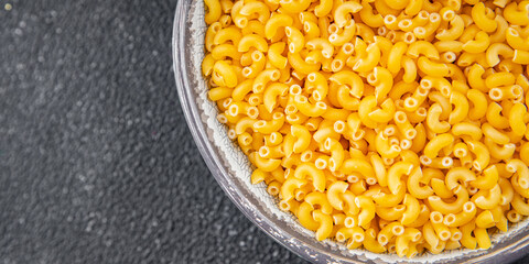 Macaroni pasta raw coquillette appetizer dish organic product fresh tasty gourmet food background on the table rustic food top view copy space