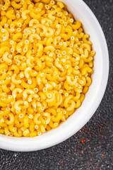 Macaroni pasta raw coquillette appetizer dish organic product fresh tasty gourmet food background on the table rustic food top view copy space