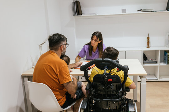 Doctor talking to father with disabled son in wheelchair