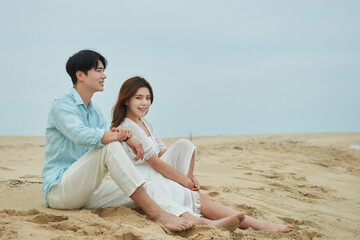 Fototapeta premium Romantic Couple Man and Woman Sitting on Beach