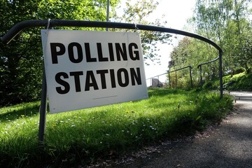 Entrance sign for the polling station located near a church building in the UK