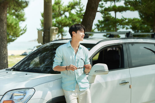 Young Asian Man Leaning on White Car Outdoors