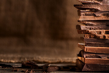 Artisanal dark and milk chocolate pieces stacked on the right side of the image, with a blurred...