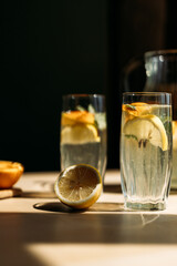 Close-up of two glasses of lemonade with fresh lemon slices and mint leaves on a wooden table. Sunlight enhances the freshness, making it ideal for food and beverage marketing.
