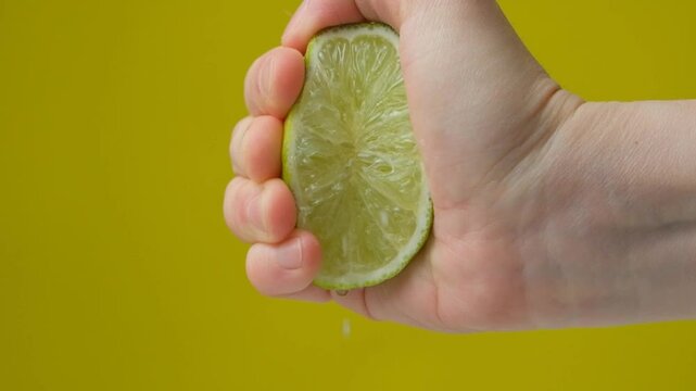 Hand Squeezing Lime. Juice Splash in Slow Motion.