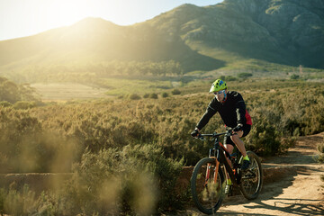 Naklejka premium Man, cyclist and mountain bike with dirt road for cardio workout, outdoor adventure or extreme sport in nature. Male person, bicycle and cycling with helmet for adrenaline on path or natural trail