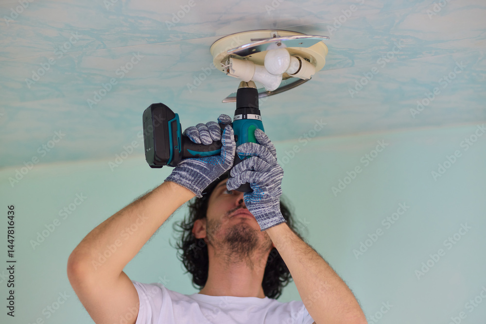 Aufkleber a person is installing a ceiling light fixture using a power tool with great care and skill
