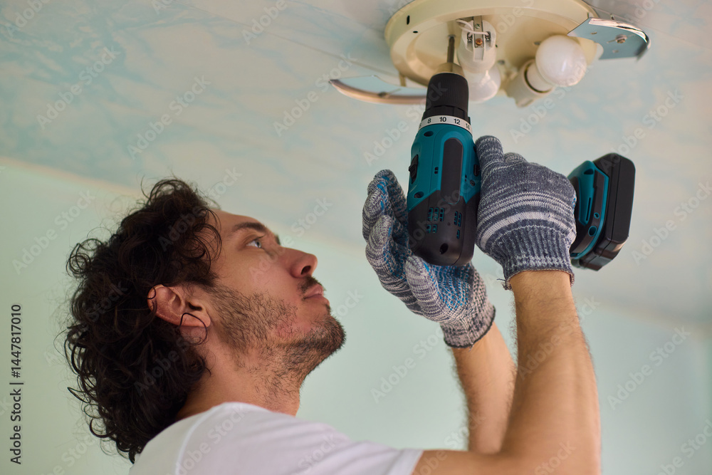 Aufkleber a person is installing a ceiling light fixture using a power tool with great care and skill