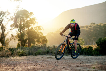 Man, cycling and nature with mountain bike for fitness, extreme sport or outdoor exercise. Active, male person or cyclist riding with bicycle or helmet for adrenaline, cardio or workout on dirt road