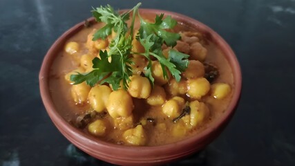 Delicious chana masala served in a traditional clay bowl, garnished with fresh coriander. A flavorful chickpea curry rich in Indian spices and perfect with rice or roti.