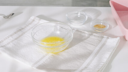 Small glass bowls with melted butter, salt, and seasoning on a towel.