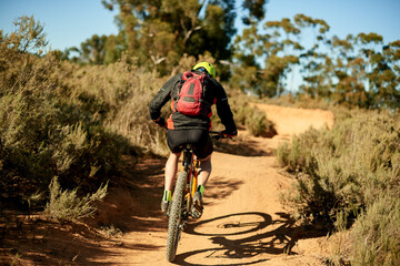 Back, man and bike on mountain for fitness, challenge and sport on dirt path. Athlete, bicycle and...