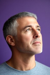 Fototapeta premium A graceful mature man with a modern hairstyle. Purple solid background. Graphic design of style for aging men. Classy men's crew cut haircut - midlife white man with grey hair.