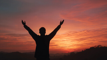 Fototapeta premium Silhouette of person raising arms in triumph at sunrise