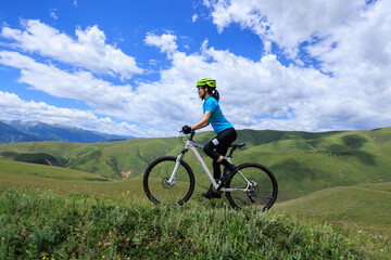 Obraz premium Asian woman riding a mountain bike down hill on beautiful mountain top