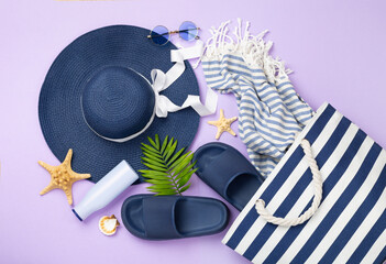 Blue beach bag with summer accessories on color background, top view