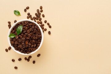 Roasted coffee beans with leaves on color background,top view