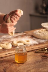 In a charming rustic kitchen flooded with morning light, a baker carefully drizzles golden, organic honey over freshly baked bread. The atmosphere is rich with sweetness