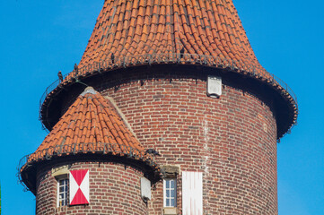 Medieval brick tower with red tile roof and birds perched on railing © Ulrich