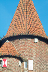 Medieval brick tower with conical tile roof reaching for the blue sky © Ulrich