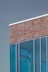 Modern building exterior showing brick wall and glass windows reflecting blue sky