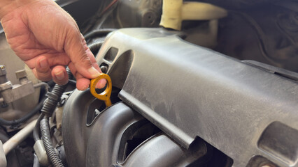 Mechanic checks the oil on a car being repaired. Hand of technician checking the oil level on dipstick in a car engine