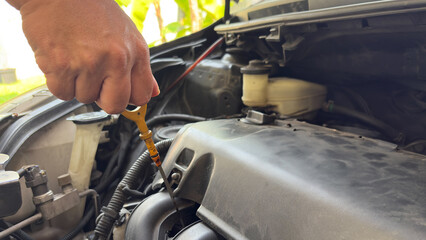Close up hand of technician checking the oil level on dipstick in a car engine. Check car oil,...