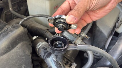Fototapeta premium Hand of car auto mechanic engine, technician service check coolant cooling fluid water, he open radiator cap for change or repair the in garage. Check car radiator, car maintenance 