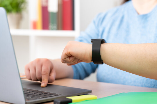 Businesswoman working and checking smart watch or clock sitting in a desktop at office