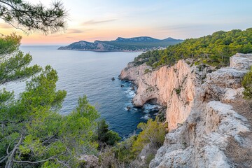 Fototapeta premium Scenic coastal view at sunset with cliffs, greenery, and distant mountains near the sea